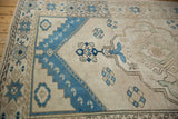 Ivory and indigo distressed Oushak rug detail showing scalloped medallion, pinwheel florals, starburst border.