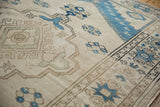 Distressed ivory Oushak rug with indigo starburst border and softened pile.
