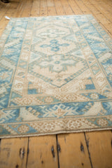 Distressed vintage Melas rug, showing worn geometric patterns in faded blues and ivory.