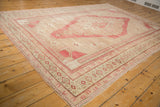 Distressed Oushak carpet side border, featuring faded geometric motifs in raspberry and beige.