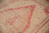 Stepped raspberry and beige border on a vintage distressed Oushak with floral motifs.