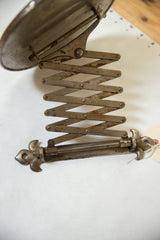Aged accordion arm with darkened patina and ornate fleur de lis hardware, circa 1910s.