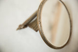 Aged metal rim of the accordion shaving mirror with darkened patina and rust spots.