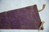 Reverse side of the vintage purple felt flag with its tan stitched edge and ties.