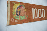 Close-up of the colorful graphic of a Native American in a headdress on a textured, rust-colored felt pennant.