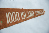 Detail of cracked white lettering and the frayed tip of the orange felt pennant.