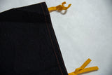 Black felt pennant edge, showcasing orange stitching and yellow ties, with soft texture.