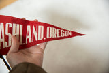 A vintage red felt Ashland, Oregon pennant held to display its tapered shape and texture.