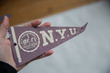Felt texture of vintage purple NYU pennant with white university seal and lettering.