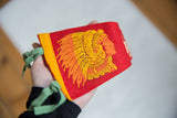 Close-up of vintage red felt pennant with orange and yellow Native American graphic.