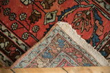 Curled corner of a hand-knotted Persian Lilihan rug, revealing woven foundation and raspberry red pile.