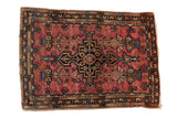 Vintage Farahan Sarouk rug with a bold charcoal medallion on a raspberry red field with blue details.