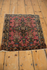Angled view of a vintage Farahan Sarouk rug with a bold geometric medallion on a raspberry red field.
