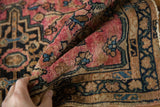 The supple, hand-knotted wool pile of a vintage Persian rug in raspberry red, blue, and charcoal tones.