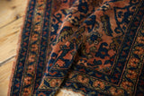 Folded vintage Lilihan rug showcasing rich terracotta rose and navy Herati floral pattern.