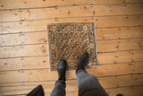 A distressed vintage Farahan Sarouk square rug mat shown from above for scale.
