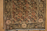 Corner detail of a vintage Persian mat showing the short pile, floral border, and original fringe.