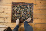 Vintage Farahan Sarouk rug corner: deep indigo field, serrated plant motifs, tattered side.