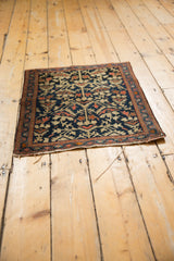 Tattered end of vintage Farahan Sarouk rug showing indigo field and serrated botanical contour.