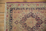 Detail of antique Kerman rug corner, showing the fuchsia purple selvage, ivory fringe, and time-softened floral pattern.