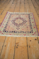 Angled view of an antique Kerman rug mat, showcasing the purple selvage and classic floral design.