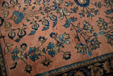 Dusty rose main field, sprawling blue blossoms, and patterned border on a vintage Sarouk rug.