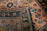 Vintage Mohajeran Sarouk rug corner, navy blue border, dusty rose floral spray field, black bound edge.