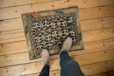 Upper corner of vintage Caucasian rug, geometric border, worn navy blue, beige, and orange pile.