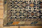Corner of vintage Caucasian rug with geometric blue serpent border and tangerine accents.