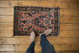 Vintage Lilihan rug corner detail, showing faded raspberry field and blue meandering floral border.