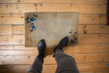 A small antique Peking rug mat with blue florals shown to scale on a wood floor.