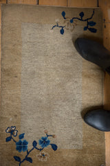 Low pile texture and blue floral corner motif on an antique Peking open field rug.