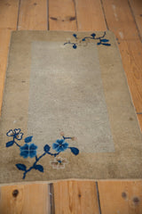 Angled perspective of an antique Peking mat highlighting its sprawling blue floral corner motifs.