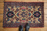 Vintage Lilihan rug corner shows blush, blue geometric motifs and tattered border.