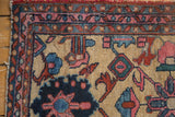 Lilihan rug border corner, showing meandering vine motif, blush pink, navy blue, and worn side.