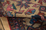 Vintage Lilihan rug's rolled pile texture, revealing geometric designs in blush, blue, and red.