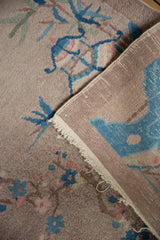 Vintage Art Deco rug corner displaying plush dusty mauve pile, sky blue motifs, and hand-knotted foundation.