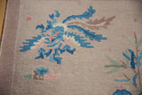 Art Deco rug detail: stylized blue, pink, and brown cloudband motif on beige with mauve selvage.
