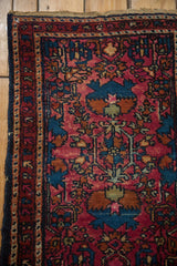 Persian Lilihan rug corner, raspberry red field, sapphire floral vinery, navy selvage.