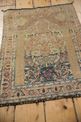 Distressed vintage Tabriz rug, showing worn floral motifs in beige, rust, and navy blue.