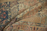 Distressed pile of a vintage Tabriz rug, revealing faint foundation, beige, rust, and navy floral elements.