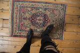 Antique Kerman rug with red and navy starburst medallion, viewed from above to show its scale.