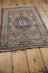 Antique Kerman rug shown from a low angle, highlighting the texture and time-softened colors.