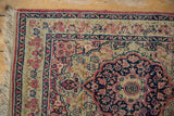 Navy blue corner spandrel and detailed millefleur border on an antique Persian Kerman rug.
