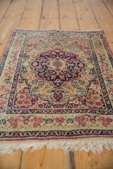 Angled perspective across the low, hand-knotted pile of an antique Kerman rug toward its medallion.