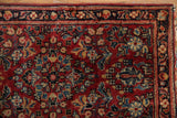 Hand-knotted Sarouk rug detail showing brick red field, floral spray, and vine.