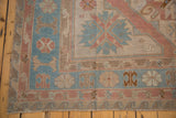 Distressed vintage Soumac carpet corner with dusty rose, blue geometric pattern and fringe.