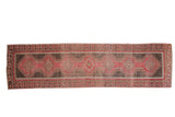 Vintage distressed Oushak rug runner with a column of red gul medallions on a time-softened, abrashed brown field.