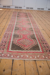 Angled view down the length of a distressed Oushak runner showing its repeating gul motif.
