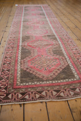 Angled view down the length of a distressed Oushak runner with repeating red and silver medallion guls.